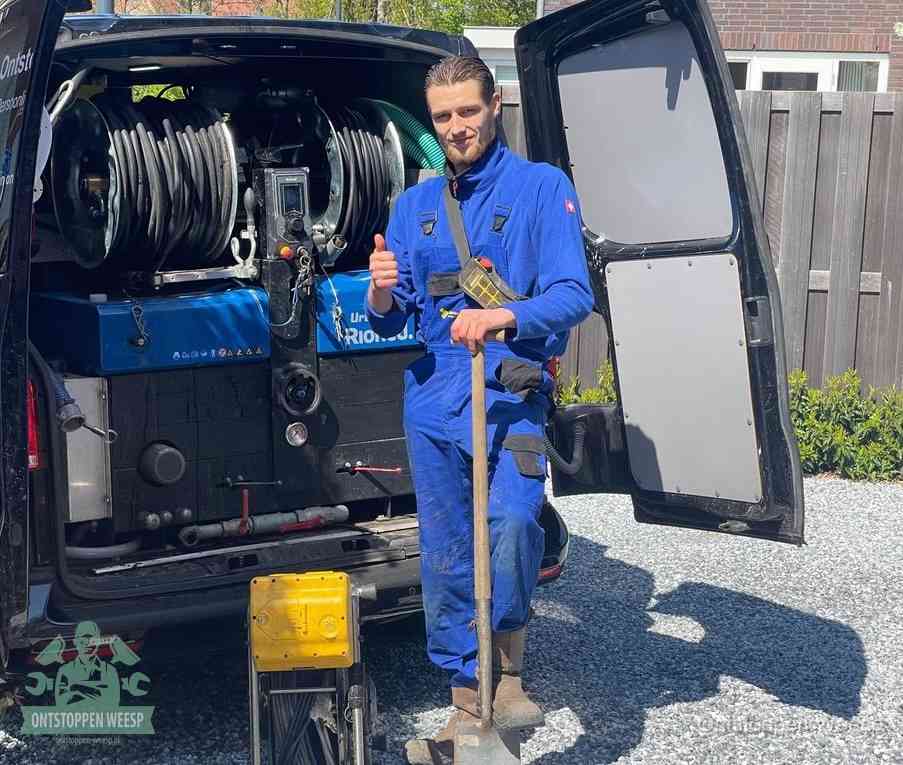 Een tevreden monteur met opgestoken duim naast de bestelbus, slim en snel ingrijpen bespaart geld bij een verstopping in Weesp