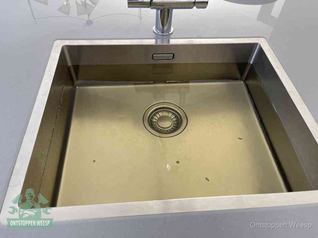 Een RVS spoelbak met stilstaand water dat niet wegloopt, een van de eerste signalen van een beginnende verstopping in Weesp