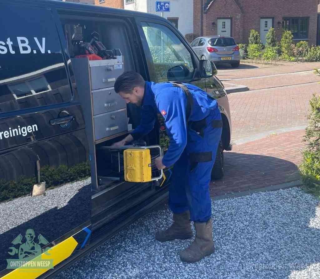 Een monteur pakt gereedschap uit de bedrijfsbus, het moment om een professionele ontstoppingsdienst in te schakelen in Weesp